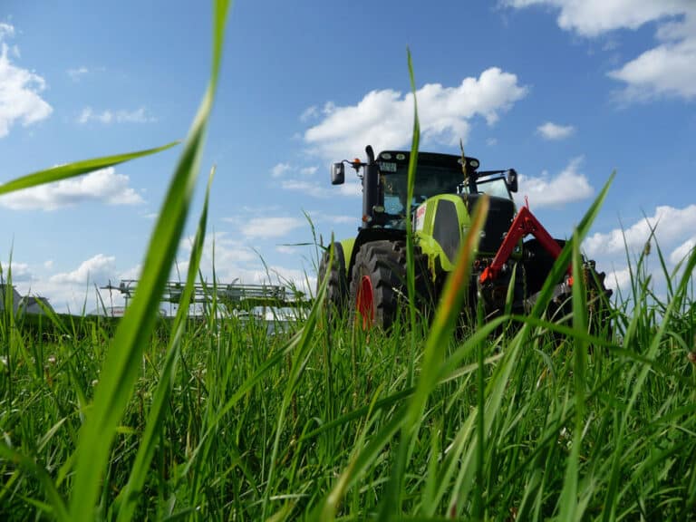 Bild eines Traktors, der über eine Wiese fährt.