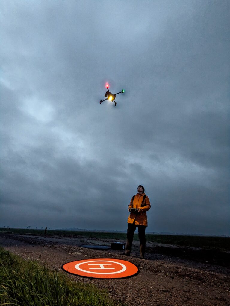 DJI Enterprise Matrice 30T Drohne startet in der Dämmerung von einem orangen Landepad.